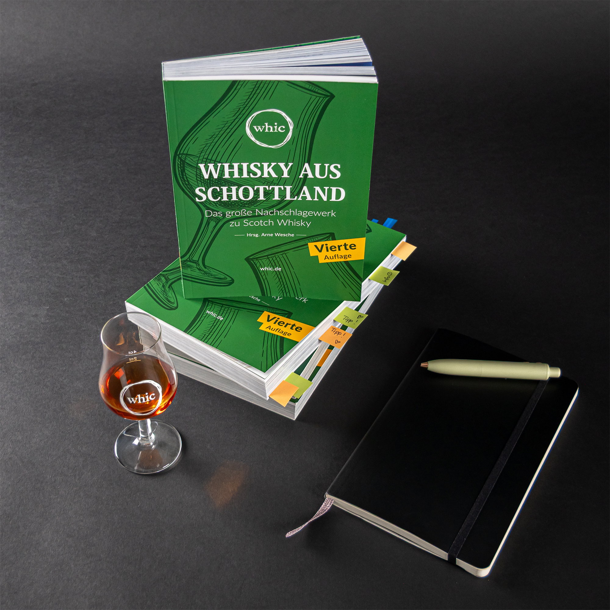 Buch Whisky aus Schottland - Das große Nachschlagewerk zu Scotch Whisky von Arne Wesche mit Notizbuch, Whiskyglas und Lesezeichen auf schwarzem Hintergrund