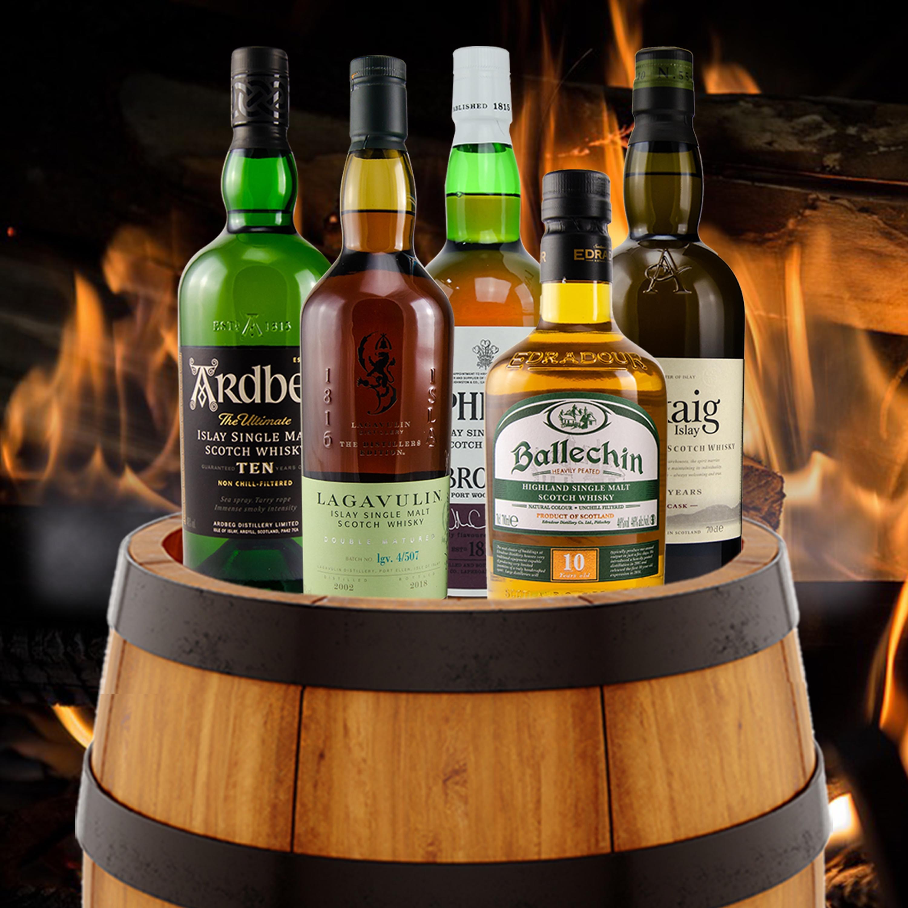 Fünf Premium-Islay- und Highland Single Malt Scotch Whiskys inkl. Ardbeg Ten, Lagavulin 16, Ballechin 10 auf Holzfass vor Feuerplatz