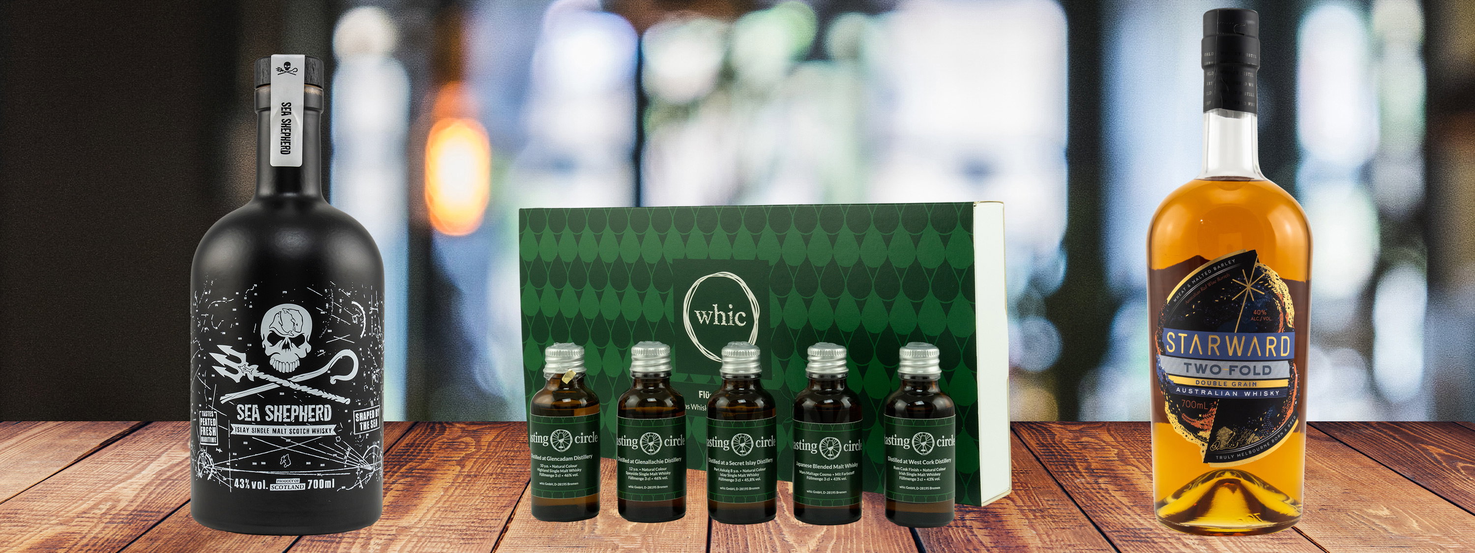 Starward Two Fold Australian Whisky 40% vol. neben Sea Shepherd 43% vol. Single Malt Scotch Whisky und 5 Tasting Circle Whisky-Proben-Set in grüner Geschenkbox auf Holztisch
